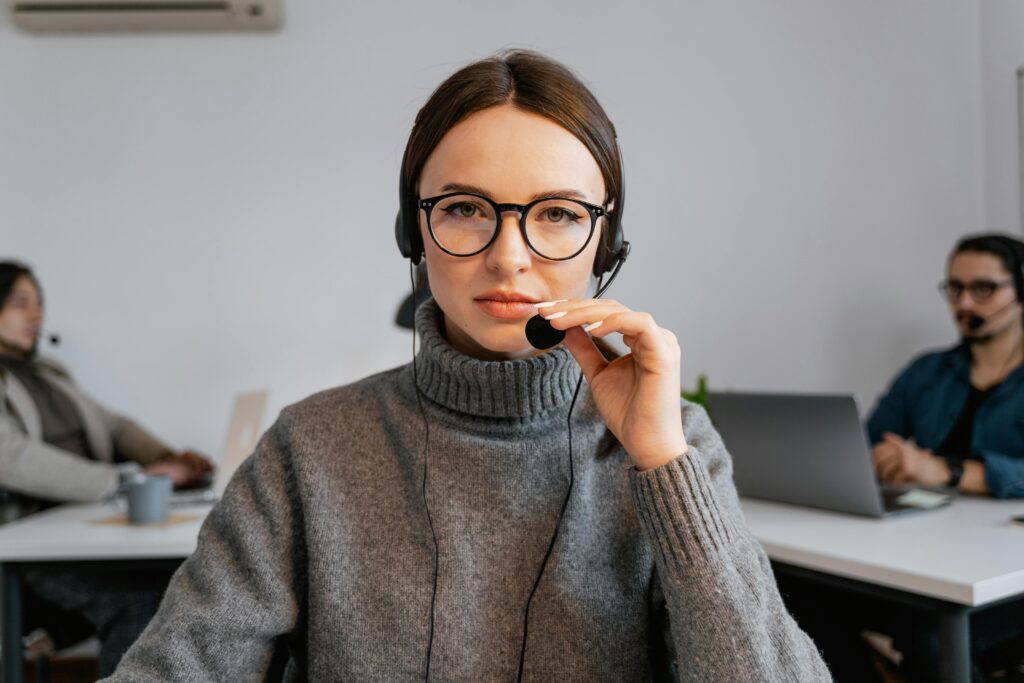 pexels photo 7709207 7709207 A focused call center agent with glasses and headset in a modern office setting.